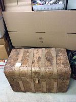 Photo of the exterior top and front of the antique wooden trunk showing metal bands and aged wood.