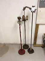 Overview photo showing three vintage floor lamps, tallest approx 56 inches tall, various metal styles and colors