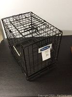 Black Petmate metal wire kennel crate showing front and top sides with label and door latch.
