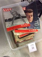 Bin of stacked Life magazines including Marilyn Monroe and John F. Kennedy covers visible