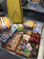 Photo showing two yellow helmets, some small toys and dolls, ink stamps, bowling game pieces, and dominoes.
