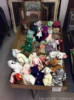 Photo showing two boxes filled with various Ty Beanie Babies in different animal shapes and colors. Includes bears, a zebra, panda, turkey, bunny and other characters all with original Ty tags.