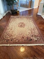 Full view of the floral throw rug laid out on wooden floor showing overall pattern and border details.