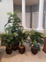 Full view of four artificial plants in decorative plastic pots showing their relative sizes and placement indoors.