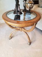 Full view of round accent table with glass top displaying the faux leather resin frame and glass surface with decorative items.