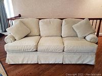 Front view of beige sleeper sofa with three seat cushions and two throw pillows