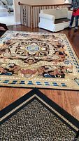 Full view of rug laid out on hardwood floor showing entire medallion pattern and border