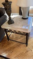 Full view of square stone top side table with metal base and two lamps on tabletop