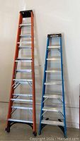 Front view of both ladders side by side showing full height and profiles; left is the orange 10 ft Husky, right is the blue 8 ft Werner.