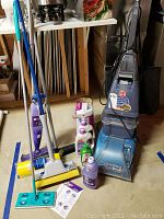 Full view of the Hoover SteamVac Spin Scrub floor cleaner with multiple mop attachments and cleaning liquids arranged around it.