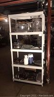 Full shelving unit loaded with servingware including glass bowls, pitchers, wire baskets, plastic bowls, trays, and beverage dispenser.