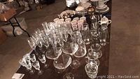 Wide shot showing variety of glassware including champagne flutes, martini glasses, tall glasses, mugs, French presses, pitcher, teapot, and creamer