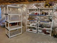 Photo of three white plastic shelving units against a foil insulated wall, showing general condition and shelving design.