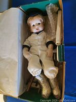 Baseball Boy porcelain doll in box with hands and feet wrapped for protection.
