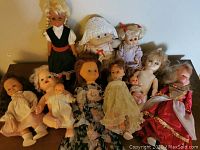 Group shot of 11 assorted dolls, including dressed dolls and baby dolls, showing different styles and sizes