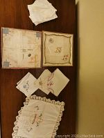 Top view of various handkerchiefs on wooden surface, including boxed sets and multiple embroidered pieces.