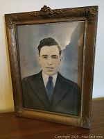 Front view of framed portrait of a man in suit and tie, showing decorative wooden frame with floral motifs.