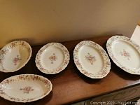 Full set of five Thomas Ivory dinnerware pieces arranged on a table showing three oval platters and two oval bowls with floral designs.