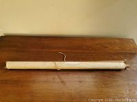 Photo of the rolled map laid on a wooden surface, showing the wooden ends and string for hanging.