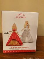 Box of the Hallmark Keepsake Barbie Celebration Ornament Set featuring 2 ornaments inspired by 2013 and 2014 Holiday Barbies.