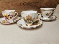 Three tea cups with matching saucers displayed side by side: Colclough Royal Visit to Canada, Royal Vale floral pattern, and Royal Standard floral pattern.