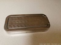 Closed metal case with engraved Greek key pattern and Rolls Razor logo on the lid.