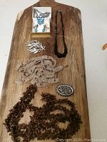 Overview of all jewelry items in the lot including necklaces, brooches, and earrings arranged on wooden surface.