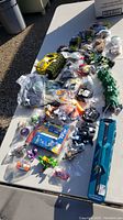 Overview of all assorted toys laid out on a white flat surface, showing various mini cars, figures, and accessories.