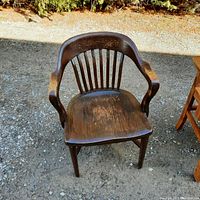 Front view of dark wood barrister chair showing wooden slat back, curved armrests, and wooden seat.