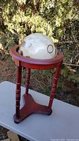Globe on wooden stand, showing the globe head and part of the stand with turned legs and triangular base.