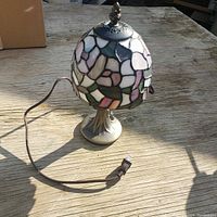 Full lamp photo showing stained glass shade and metal base with electric cord and plug