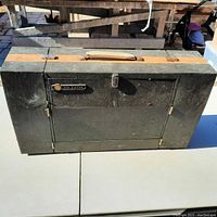 Closed RCA Victor portable record player in a black textured suitcase case with tan handle and metal latch.