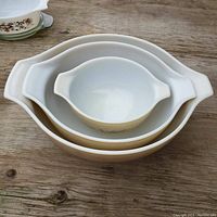 Top view of 3 nesting Pyrex bowls stacked inside each other showing bowls' shapes and handles