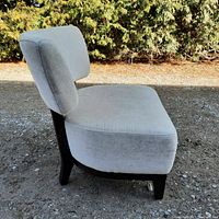 Side view of the slipper chair showing thick seat cushion, backrest, and dark wooden legs.