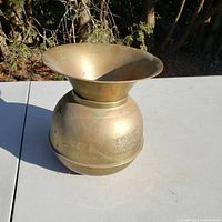 Full view of union pacific brass spittoon on white table outside.
