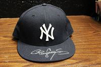 Front view of the navy blue New York Yankees baseball cap with white embroidered NY logo and Roger Clemens autograph in silver on front brim.