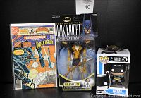 Photo of lot showing comic book, action figure in packaging, Funko Pop figure box, and Hot Wheels Batmobile on top of the box.