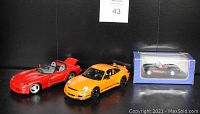 Photo showing three die-cast model cars: red Dodge Viper, yellow Porsche 911 in styrofoam, and boxed black/red 1957 Corvette.