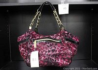 Fuchsia flocked cheetah print satchel purse with gold-tone chain handles, outer zippered pocket, black and white interior lining, and tags attached.