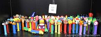 Full view of a large collection of vintage PEZ dispensers with diverse character heads arranged side by side.