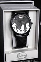 Front view of the Disney black glitter princess watch with silhouettes of three princesses and mirrored crown on dial, mounted in original white box.