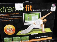Front of the original packaging showing a woman performing yoga on the interactive fitness mat, highlighting the key features like over 80 exercises and personalized workouts.