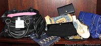 Lot of purses, clutches, and wallets displayed together on a wooden surface