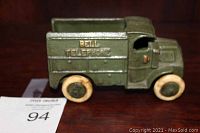 Front-side view of antique metal toy truck in green with Bell Telephone logo and white wheels.