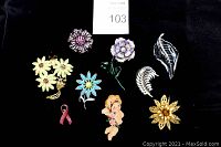 All 9 vintage brooches arranged on black background, showing varying floral and decorative styles, colors include pink, blue, gold, silver, purple, and cream.
