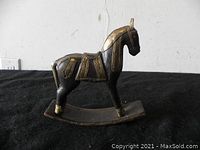 Side view showing the overall shape, curved rocker base and detailed carving with gold accents.