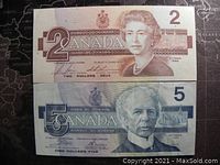 Front side of 1986 Canadian $2 and $5 banknotes showing portraits and denominations