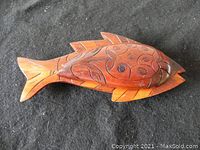 Wooden fish-shaped tray with attached carved lid on dark surface