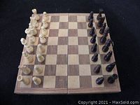 Top view of wooden chess board with all pieces set in starting positions, showing light natural wood and dark stained wooden pieces.