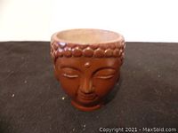 Front view showing detailed face of Buddhist head planter with textured hair curls and closed eyes.